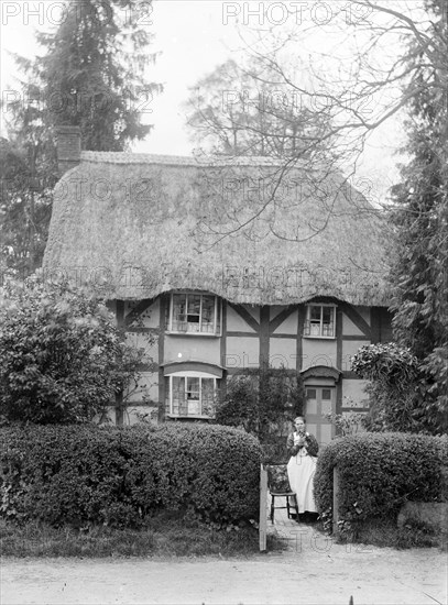 Woman holding her cat at the gate of her cottage, Uffington, Oxfordshire, c1916