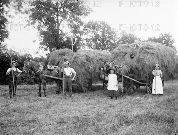 Agricultural workers pose next to loaded hay waggons near Hellidon, Northamptonshire, c1873-c1923