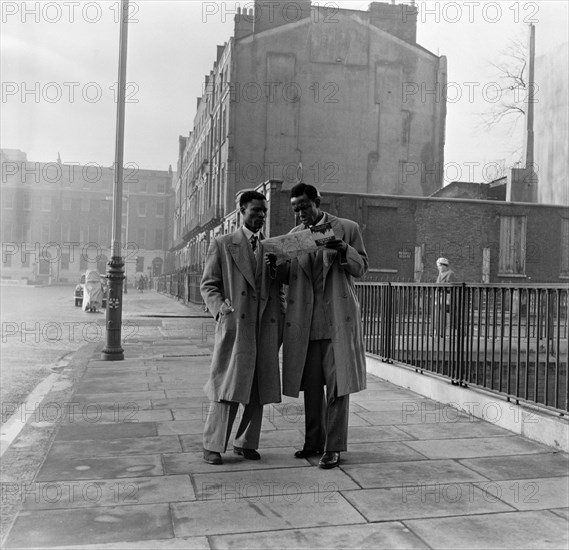 Two Afro-Caribbean men reading a map in the street, London, (c1950s?). Creator: Henry Grant.