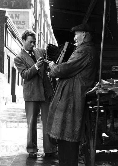 Man browsing a stall at Camden Town, 1950s. Artist: Henry Grant