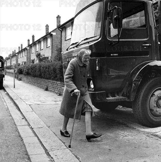 Old woman and truck on a London street, 1977. Artist: Henry Grant