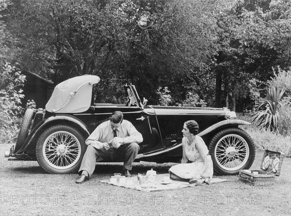 Couple having a picnic by an MG TA Midget, late 1930s. Artist: Unknown