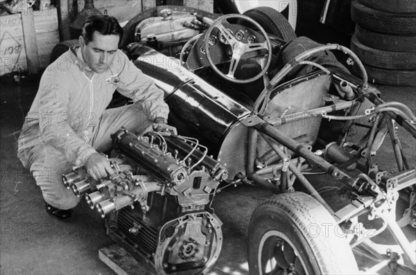 Jack Brabham inspecting the engine of a car. Artist: Unknown