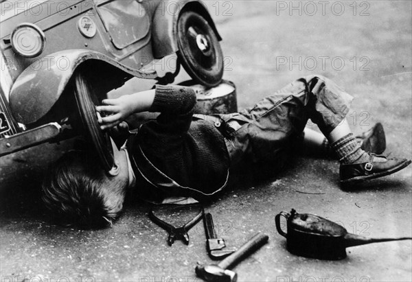 Michael Ware repairing his pedal car. Artist: Unknown