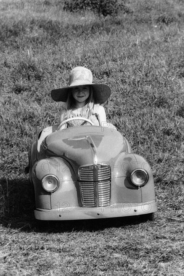 Girl in a 1948 vintage Austin J40 pedal car. Artist: Unknown