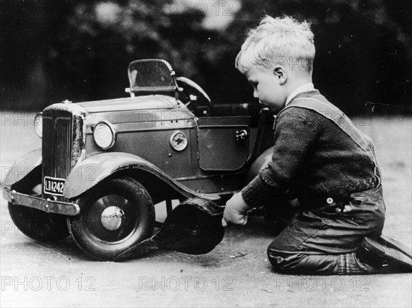 Michael Ware repairing a pedal car. Artist: Unknown