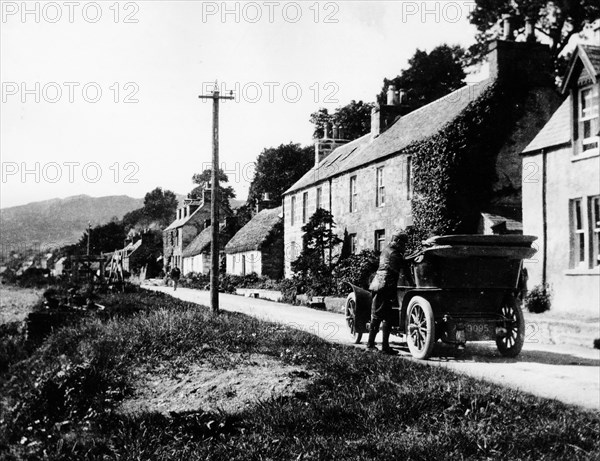 A man by his car in a village lane, 1900. Artist: Unknown