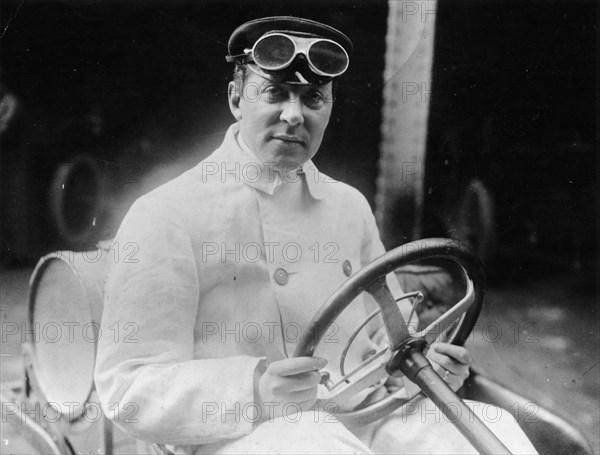 A man at the wheel of his car dressed in a driving coat and goggles. Artist: Unknown