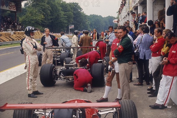 Graham Hill watches Mechanics working on a car, French Grand Prix, Rouen, 1968. Artist: Unknown