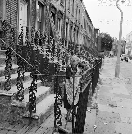 Woman sweeping front steps, London, 1960-1965