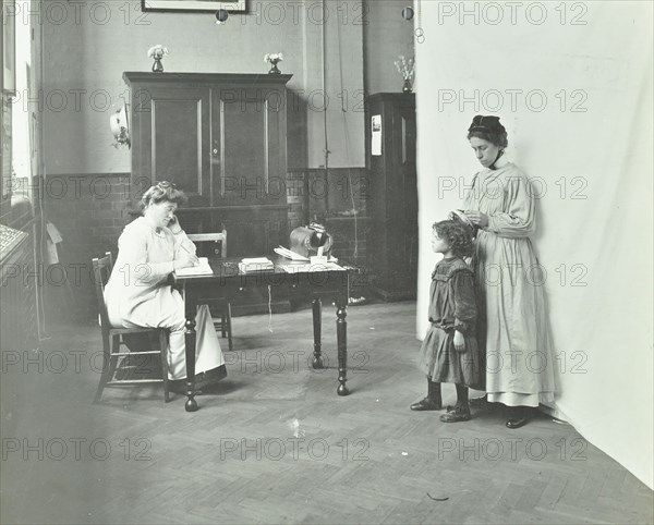 School nurse examining girls' hair for head lice, Chaucer School, London, 1911. Artist: Unknown.