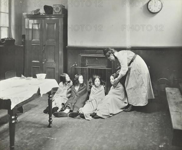 Girls drying their hair by the fire after a bath, Chaucer Cleansing Station, London, 1911. Artist: Unknown.