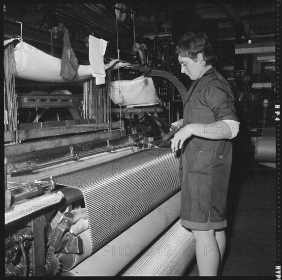 Weaver preparing a shuttle for use in a power loom, 1966-1974