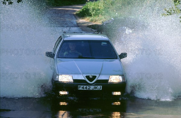 1989 Alfa Romeo 164 driving through a ford. Artist: Unknown.