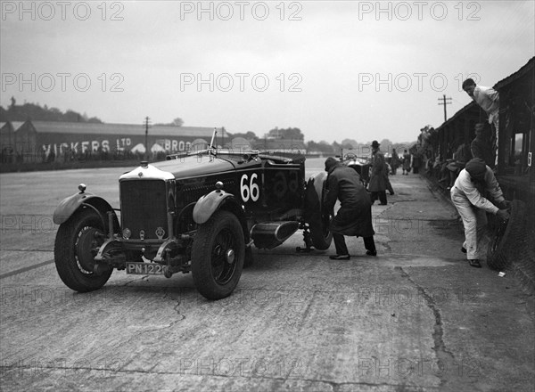 GL Baker's 5954 cc Minerva undergoing a rear wheel change at Brooklands. Artist: Bill Brunell.