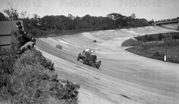 Eddie Hall's Bentley leading a Bugatti on the banking at Brooklands.   Artist: Bill Brunell.