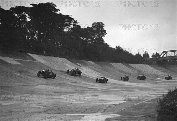 Cars racing on the banking at a JCC Members Day, Brooklands. Artist: Bill Brunell.