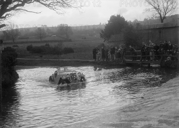 972 cc Singer Le Mans driving through a ford during a motoring trial, 1936. Artist: Bill Brunell.