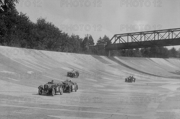 Singers of TW Fassett and Alf Langley and an MG racing at a MCC meeting, Brooklands, Surrey, 1933. Artist: Bill Brunell.