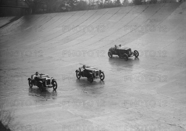 Two Austin 7s and an unidentified car racing at a BARC meeting, Brooklands, Surrey, 1931 Artist: Bill Brunell.