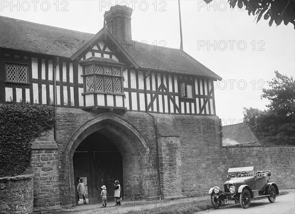 Singer 10 hp open 2-seater by the gatehouse of Stokesay Castle, Shropshire, 1920s. Artist: Bill Brunell.