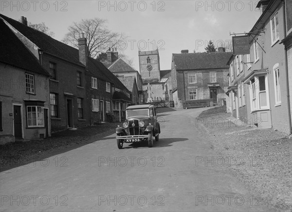 Standard Sixteen saloon driving down the High Street, Hambledon, Hampshire, 1930s. Artist: Bill Brunell.