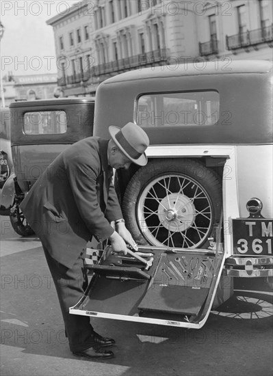 A driver opening the fitted toolkit of his Ford Model A at the Southport Rally, 1928. Artist: Bill Brunell.