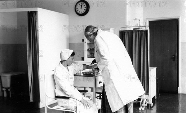 The Rowntree doctor examines the arm of a member of staff, Rowntree Factory, York, Yorkshire, 1953. Artist: Unknown