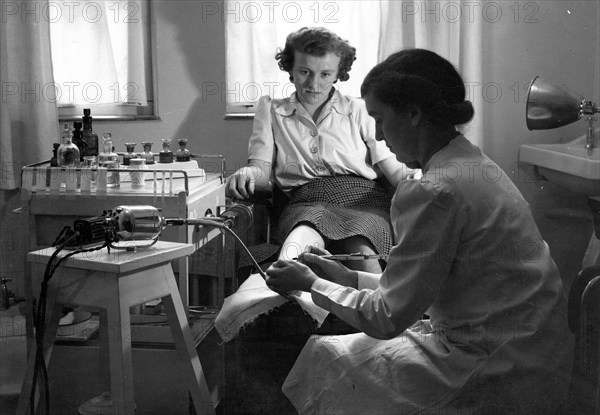 A Rowntree?s chiropodist works on a woman?s foot, York, Yorkshire, 1946. Artist: Unknown
