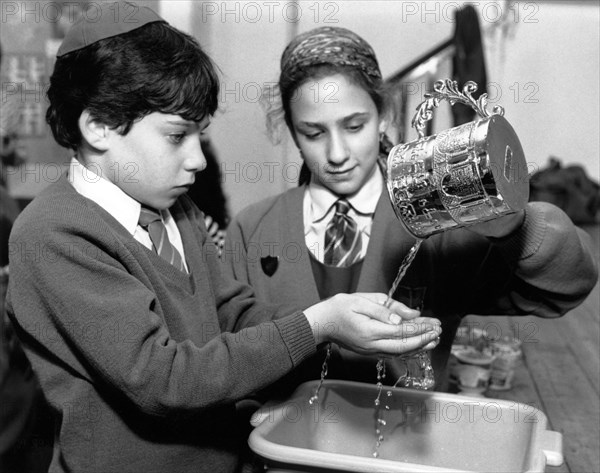 Jewish children performing ritual hand-washing, April 1991. Artist: Sidney Harris