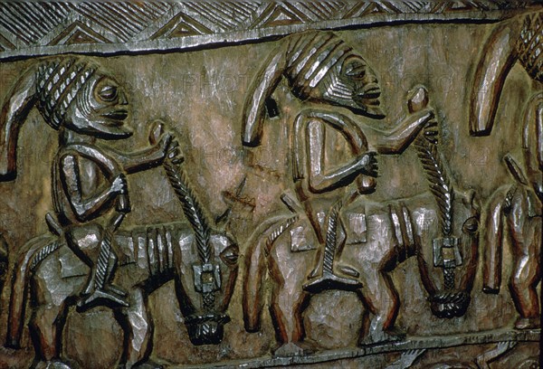 A carved wooden door from Nigeria depicting men on horseback. Artist: Unknown