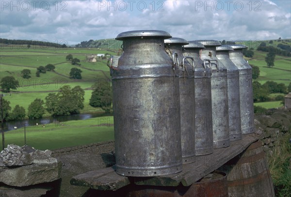 Milk cans at farm gateway.