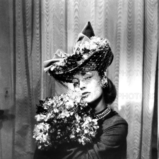 Woman wearing a hat with a veil, holding a bouquet of flowers, Paris, 1943. Artist: Unknown