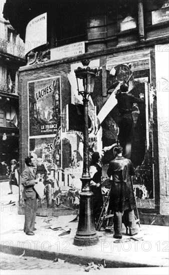 Billboard with men putting up propaganda posters, Paris, World War II, 1939-1945. Artist: Unknown