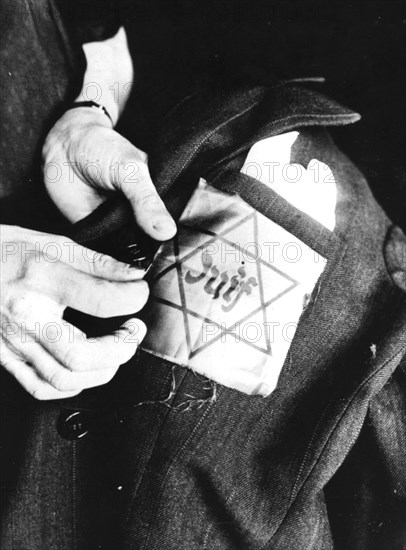 Sewing the yellow star identifying a Jew onto a jacket, German-occupied Paris, 1942. Artist: Unknown