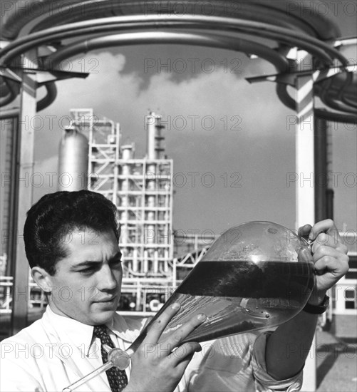 A laboratory worker holds a separating funnel of oil, Dunkirk refinery, France, 1950s. Artist: Unknown