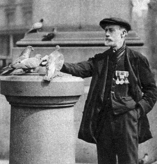 An old soldier with some pigeons, Trafalgar Square, London, 1926-1927.Artist: McLeish