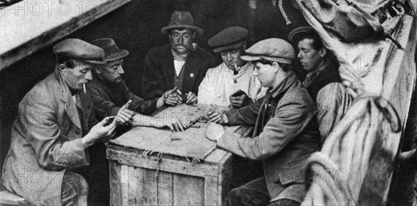 A bargee and his mates play dominoes in the hold of a canal boat, 1926-1927. Artist: Unknown