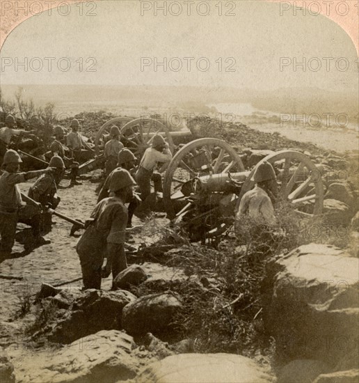 Cape Garrison artillery making it hot for the Boers across the Modder River, South Africa, 1900. Artist: Underwood & Underwood