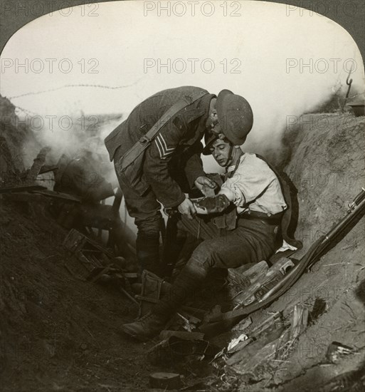 Soldier receiving first aid from a sergeant in a sap, Battle of Peronne, World War I, 1914-1918.Artist: Realistic Travels Publishers