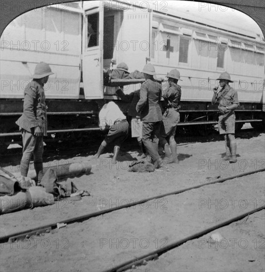 Lifting wounded soldiers onto a hospital train, East Africa, World War I, 1914-1918.Artist: Realistic Travels Publishers