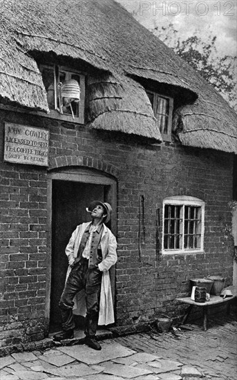 A man smoking a pipe outside a shop, Worcestershire, c1922.Artist: AW Cutler