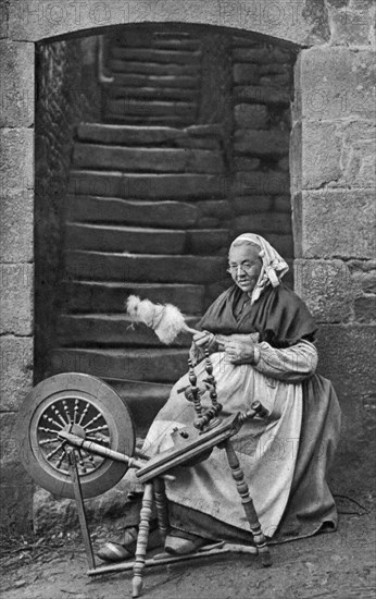 A woman at a spinning wheel, Dinan, Brittany, France, c1922. Artist: Unknown