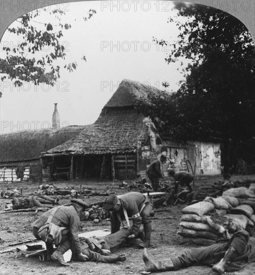 Stretcher bearers caring for wounded at an improvised first aid post, World War I, c1914-c1918.  Artist: Realistic Travels Publishers