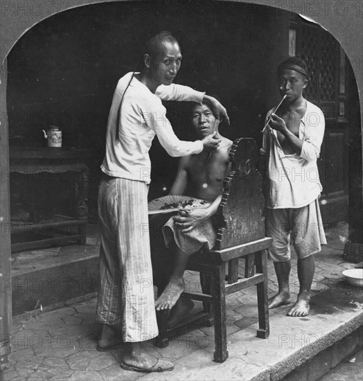 A Chinese barber at Bhamo, Burma, 1908. Artist: Stereo Travel Co