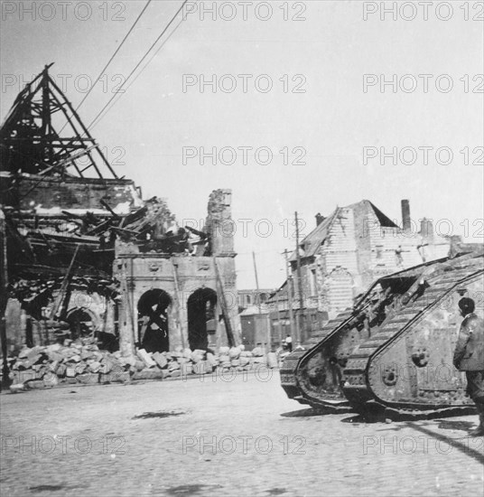 British tank in front of ruined buildings, Peronne, France, World War I, c1916-c1918. Artist: Nightingale & Co