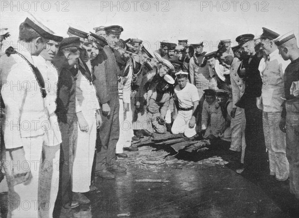 'British sailors round a hole in the deck of their vessel', 1915. Artist: Unknown.