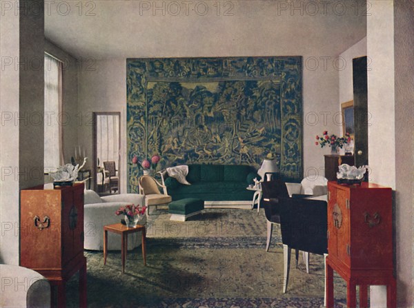 'Living-room designed by Porteneuve & Dominique, the end wall of which is hung with an old tapestry  Artist: Unknown.