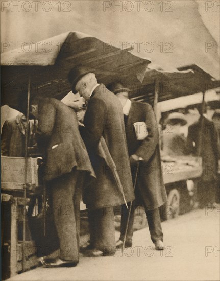 'At One of the Bookstalls of the Farringdon Road Market', c1935. Creator: Walter Benington.