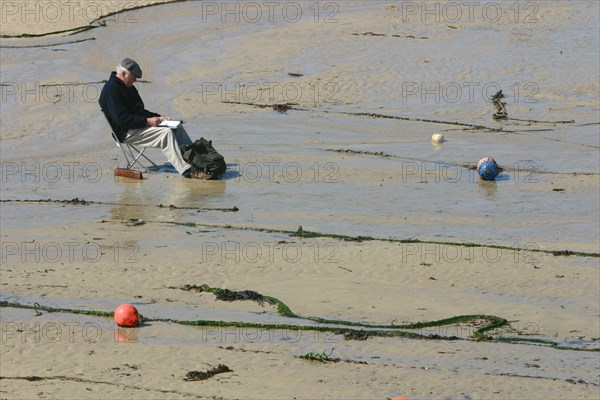 Man sitting on the sand in St Ives harbour at low tide, Cornwall